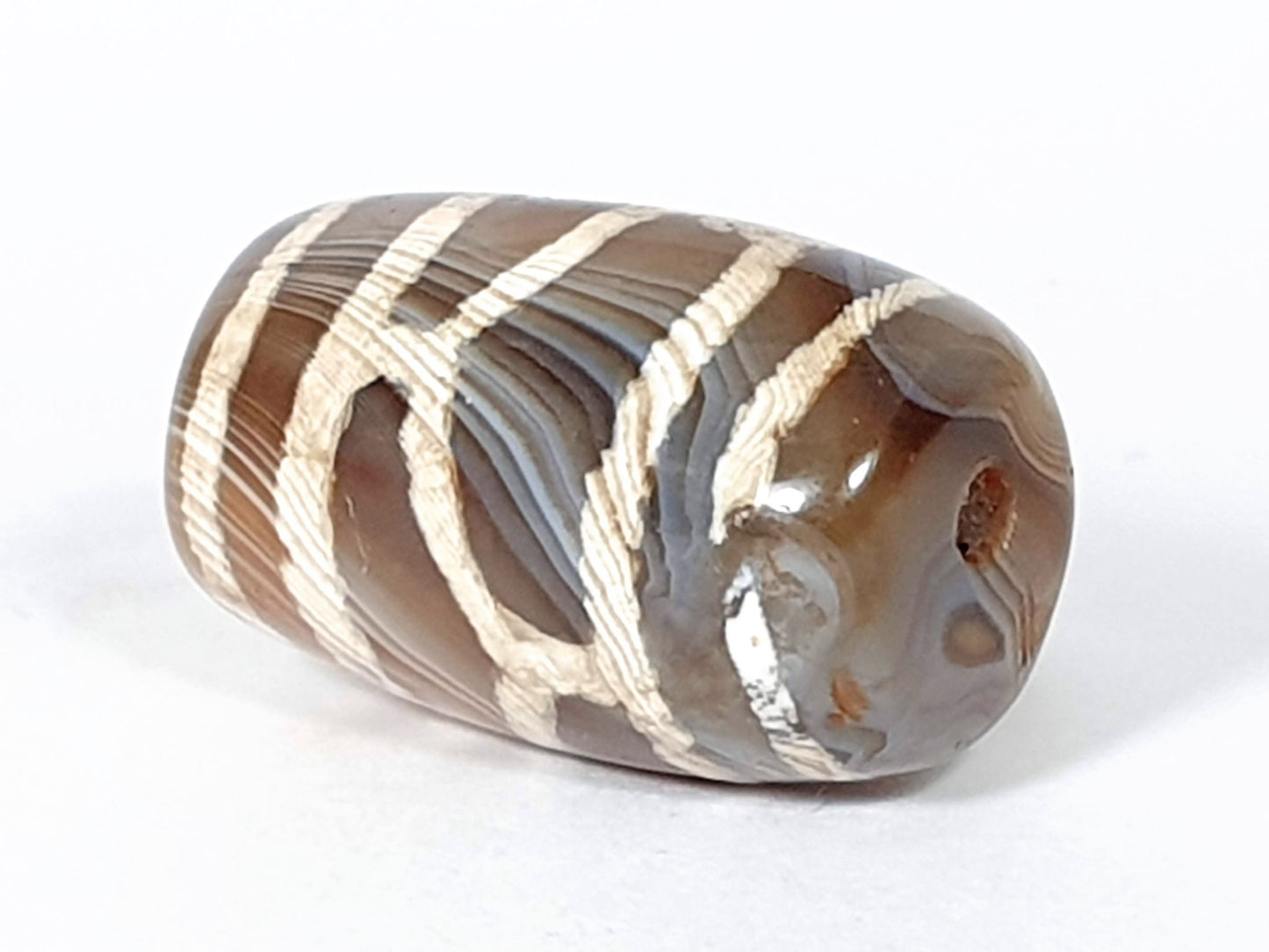 Antique longevity dzi — angled end, lattice on body, orange-red agate inclusion near drill hole tip, At-0426-Lon2