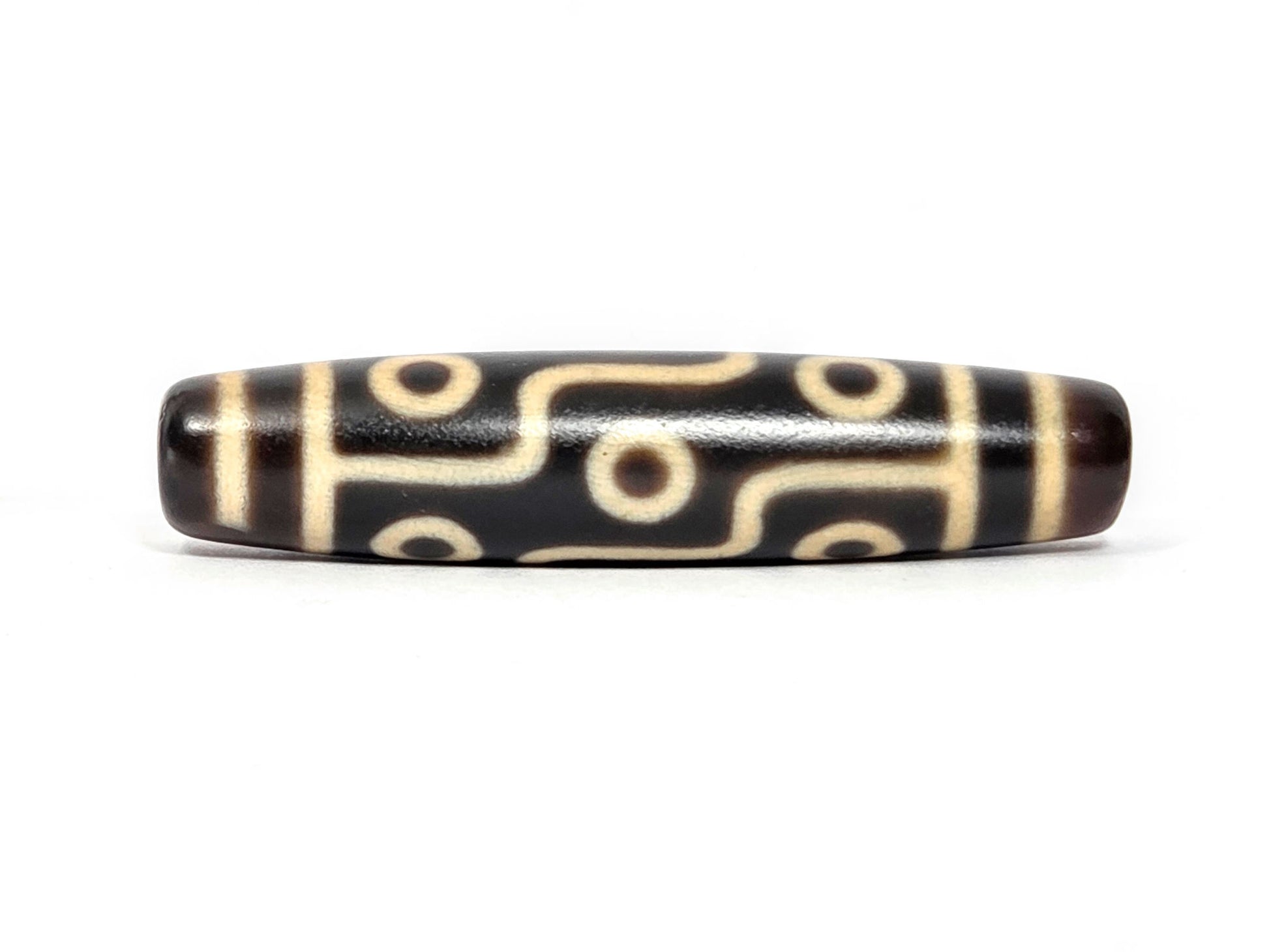 N-122225-9E Nine Eye dzi bead, alternate front angle, near-black centre, cream motif lines, unretouched