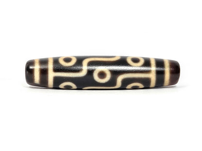 N-122225-9E Nine Eye dzi bead, alternate front angle, near-black centre, cream motif lines, unretouched