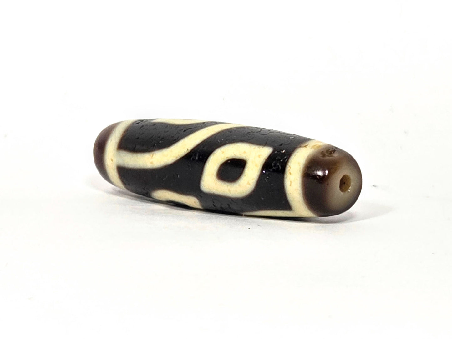 N-082825-4E angled drill-end view, dark brown end cap, eye visible near drilling, unretouched