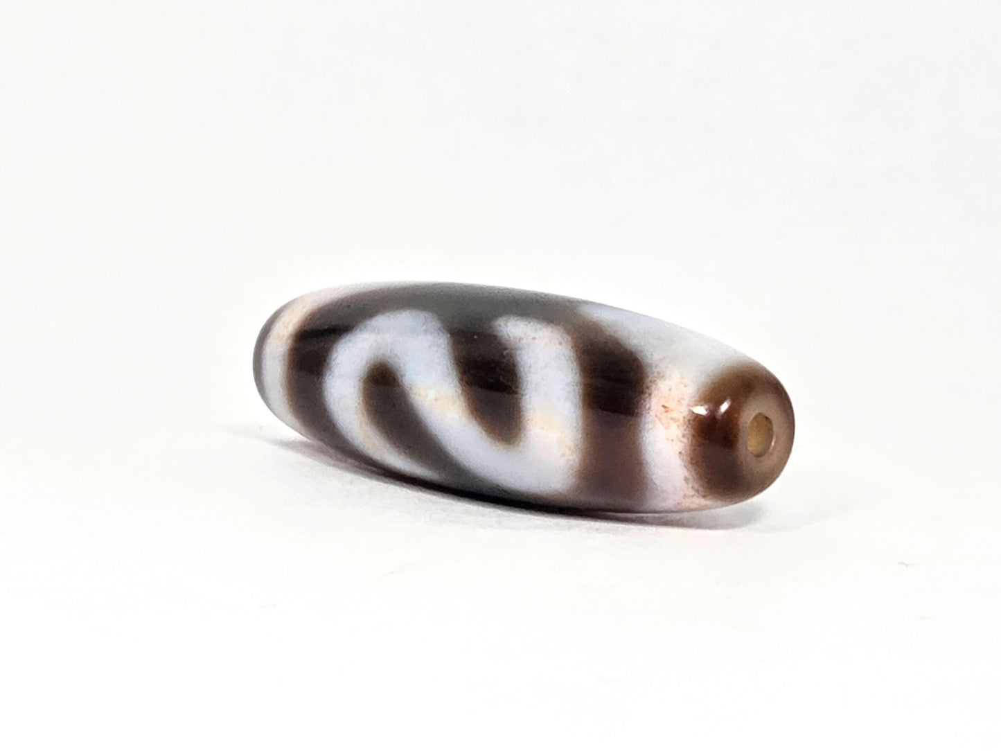N-070526-MHkBS angled drill-end view, money hook dzi, warm brown end cap, glossy agate, unretouched