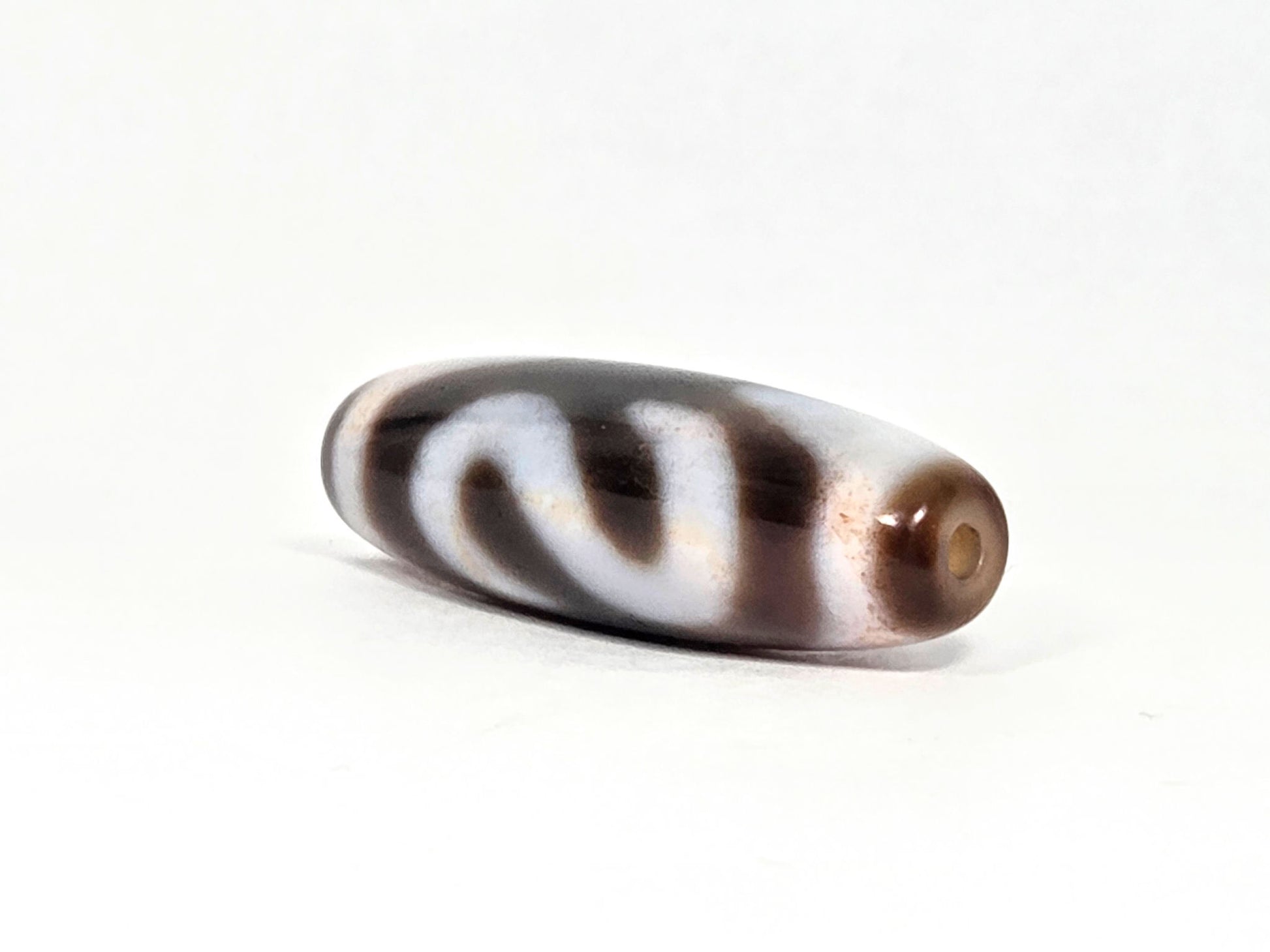 N-070526-MHkBS angled drill-end view, money hook dzi, warm brown end cap, glossy agate, unretouched