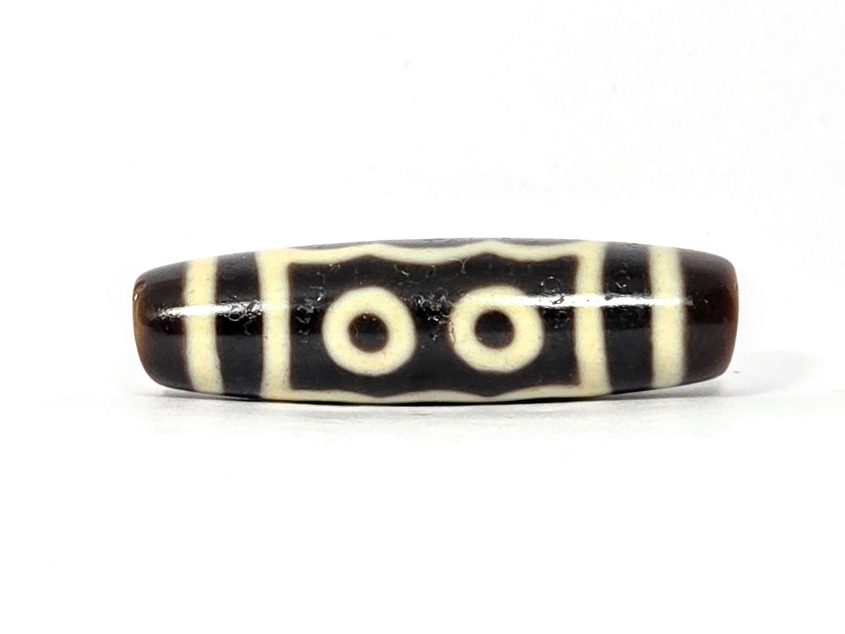 Five-eye dzi bead, very dark brown agate, cream white eye motifs, striped pattern, smooth polished surface, 40.5mm elongated oval shape