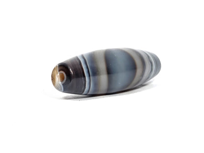N-N-080926-1E6 natural one eye dzi bead 50.5×15.8mm, opposite angled end view showing secondary naturally-formed eye at drill opening within warm brown oval, unretouched