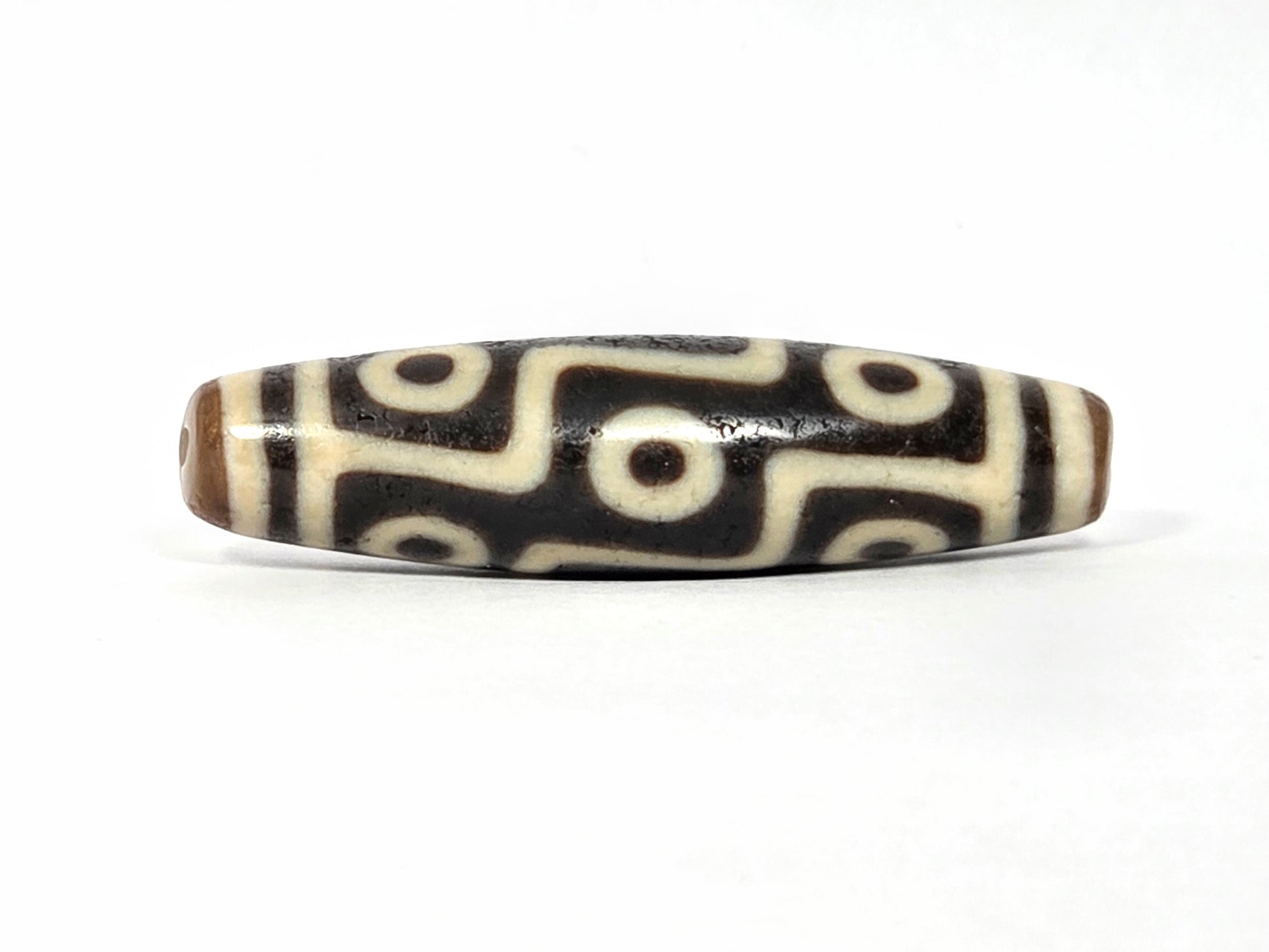 Decorative bead with black and white pattern on a white background