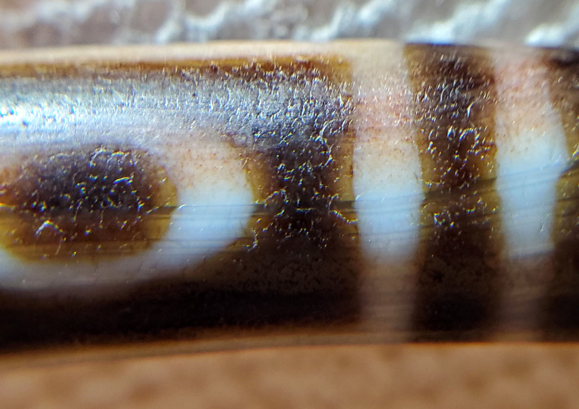 Macro: ancient dzi eye zone — micro-crystalline surface weathering and brown bloodspot pooling, Anc-0426-1EMt