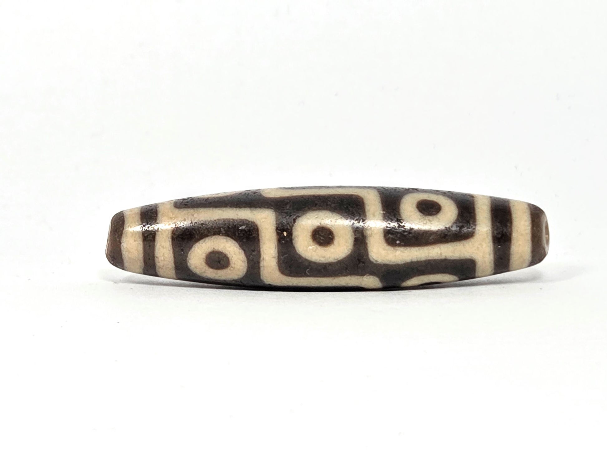 Ac-032326-9E5 Face B, three open C-ring eyes, broad cream-white connector bands, warm dark brown ground, unretouched