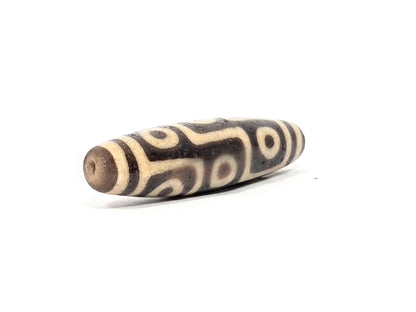 Ac-032326-9E5 left drill hole end, sandy-tan tip, age-granular cream-white surface texture visible, unretouched