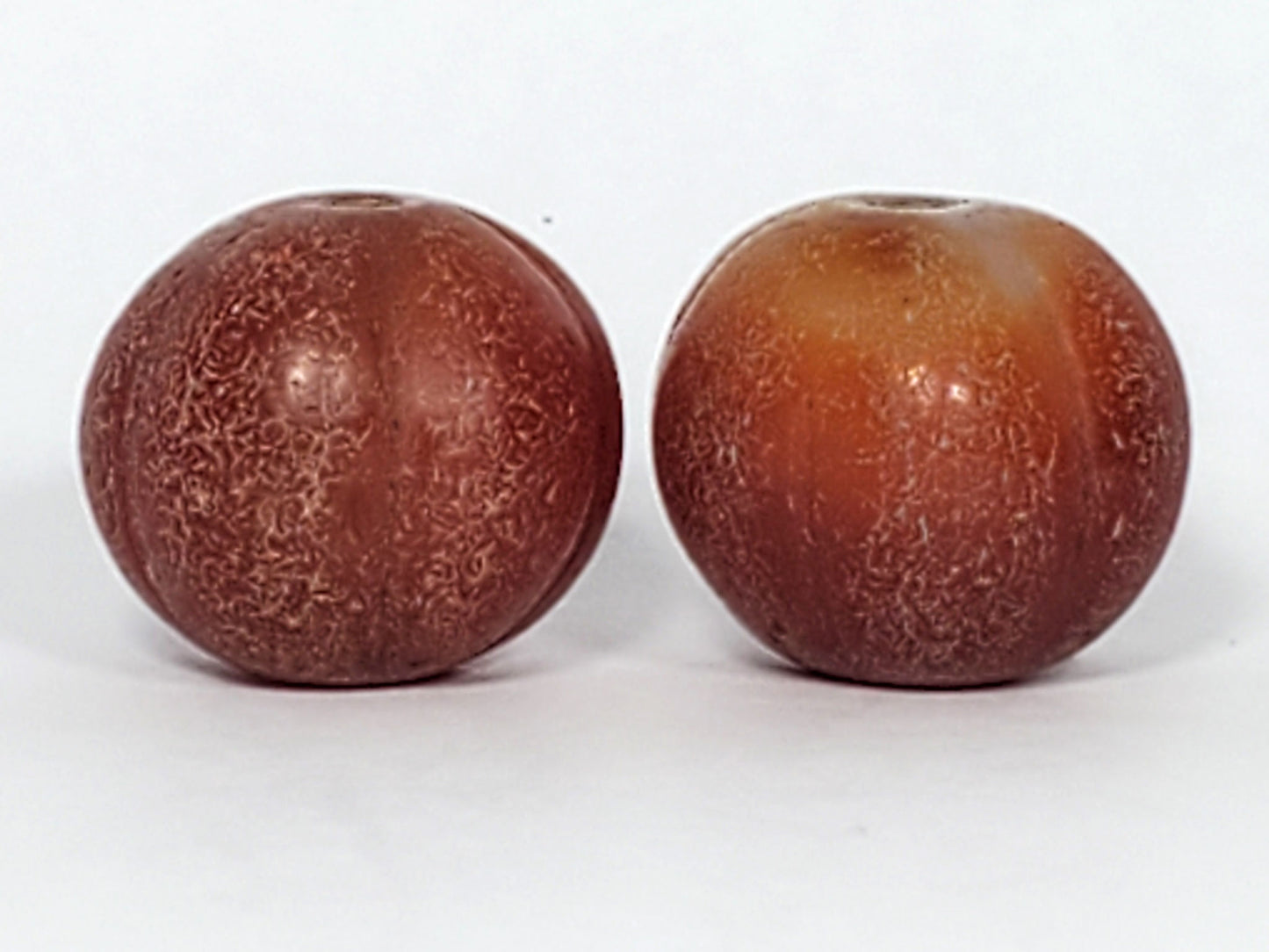 Ac-061126-PKP hero pair, reddish-brown Bead A left, honey-brown Bead B right, ribbed pumpkin form, unretouched