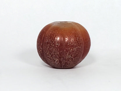Ac-061126-PKP Bead B third face, honey-gold to warm brown banding, ribbed lobed form, drill hole visible, unretouched