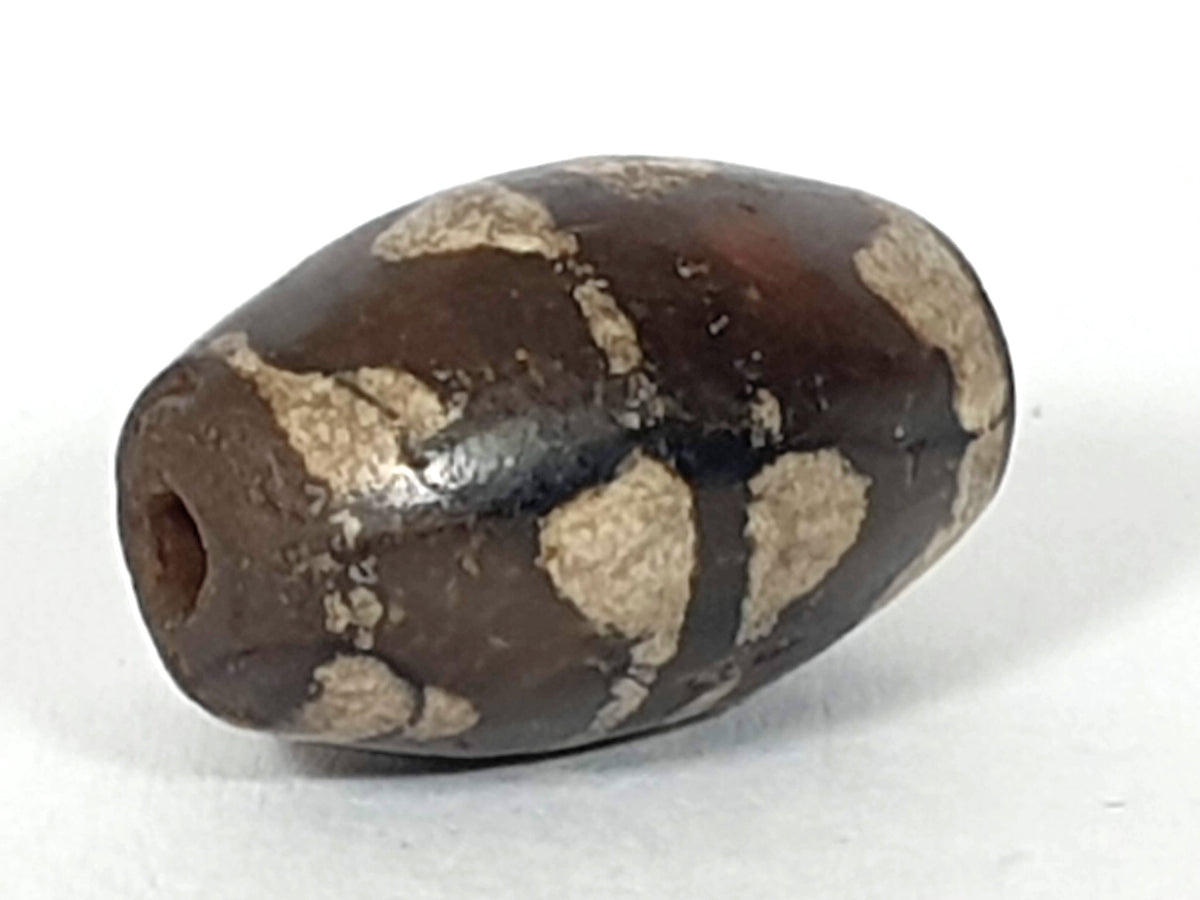 Antique double wave dzi — angled end, drill hole at dark rounded tip, wave motif on compact near-spherical body, At-0426-DW2