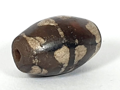 Antique double wave dzi — angled end, drill hole at dark rounded tip, wave motif on compact near-spherical body, At-0426-DW2