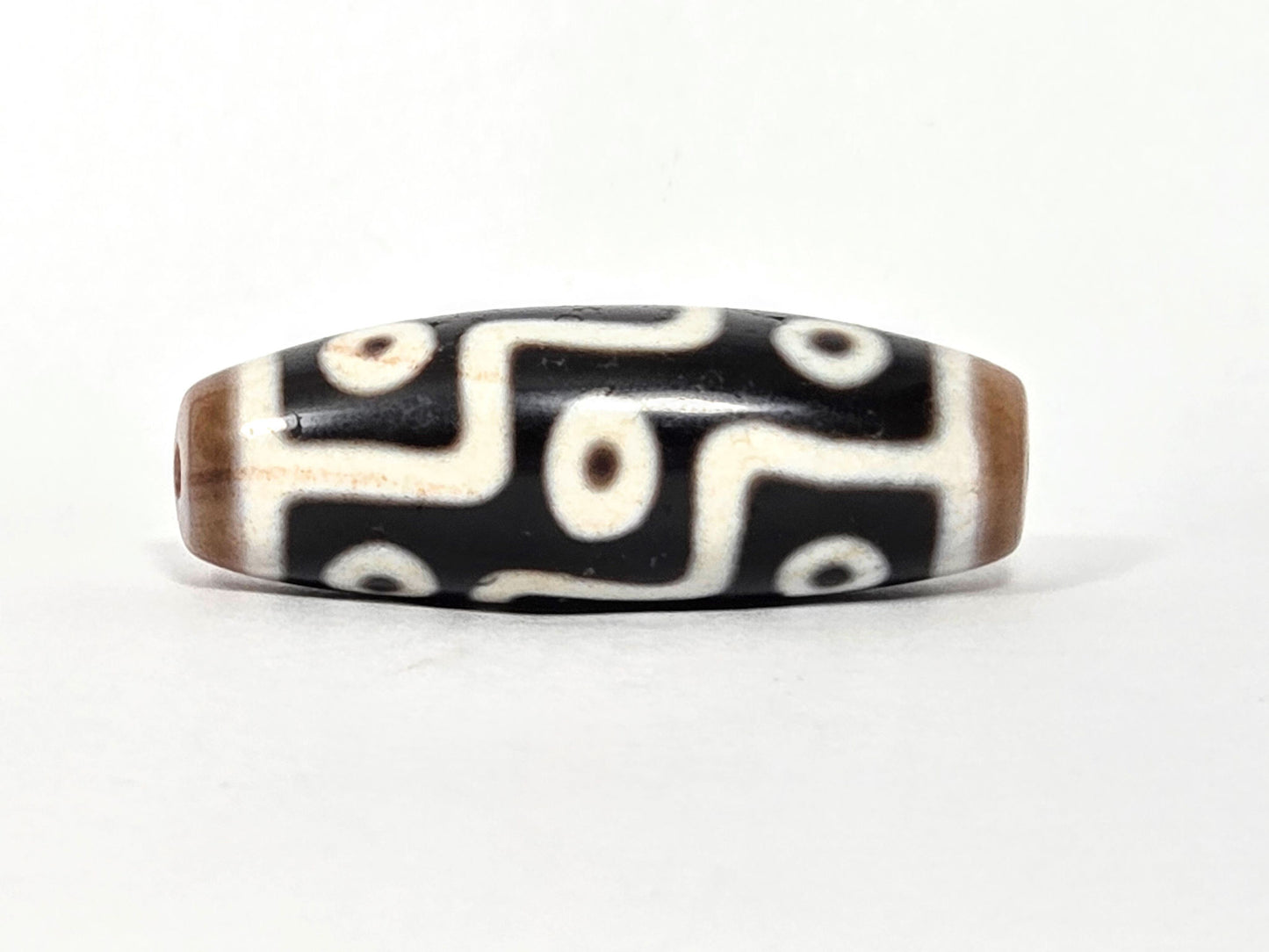 At-061926-9E6BS Face B, 5 closed ring eyes, sandy-tan end caps, pitch-black ground, cream-white motif, unretouched