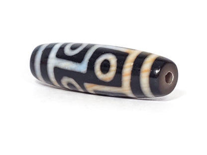 N-051423-6E dzi bead, diagonal view showing drill hole, black ground, unretouched photo.