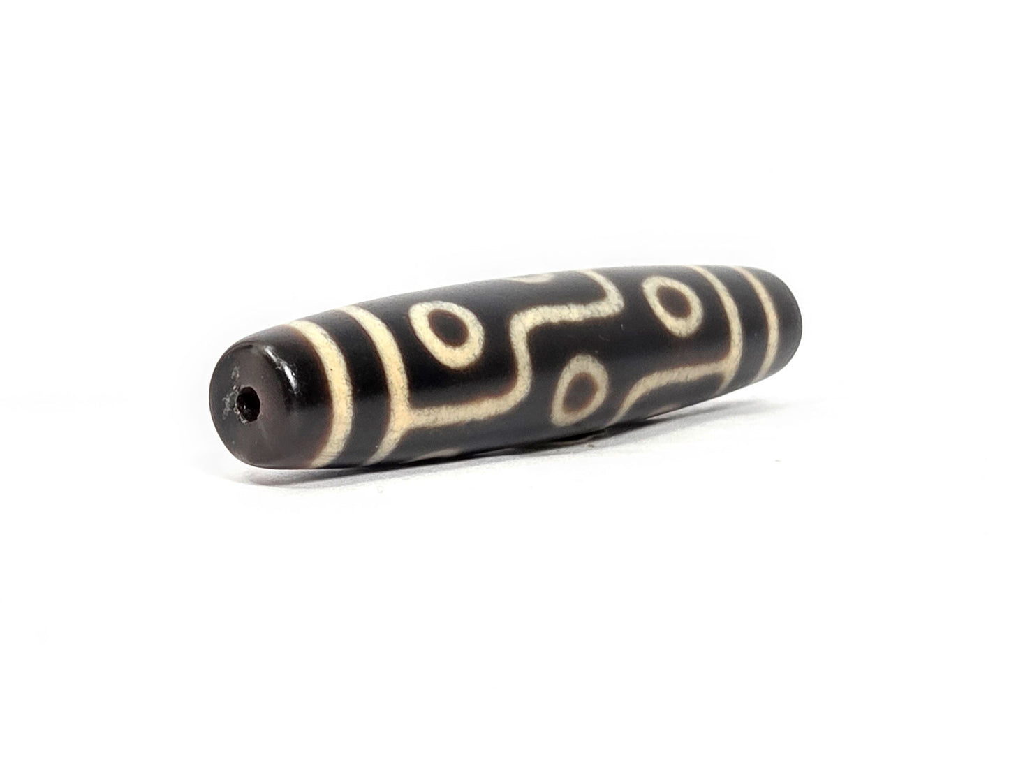 N-122325-9E Nine Eye dzi bead, opposite angled end view, consistent dark brown ground end to end, unretouched