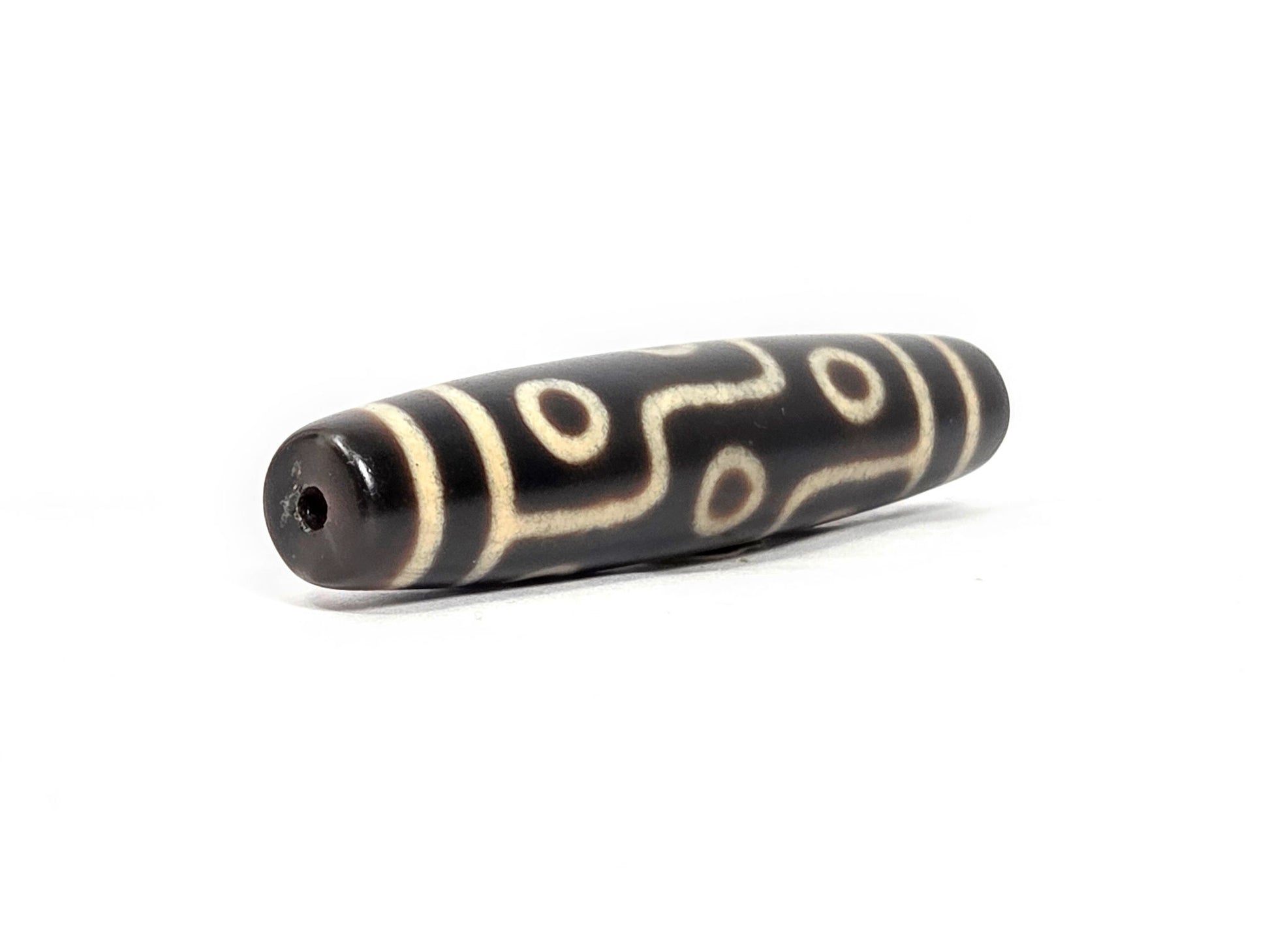 N-122325-9E Nine Eye dzi bead, opposite angled end view, consistent dark brown ground end to end, unretouched