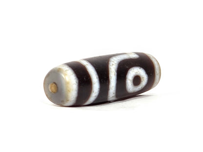 V-062126-2E dzi bead, opposite angled view showing end cap and drill hole, unretouched