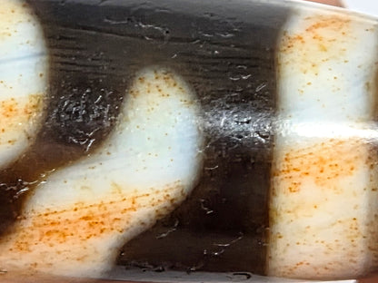 V-021326-BenBS vintage Benefactor dzi bead, macro body zone, boundary-concentrated cinnabar at cream-dark edges, unretouched.