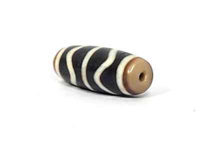 V-071425-DW vintage double wave dzi, angled end shot, warm tan-brown drill end cap and drill hole visible, unretouched.