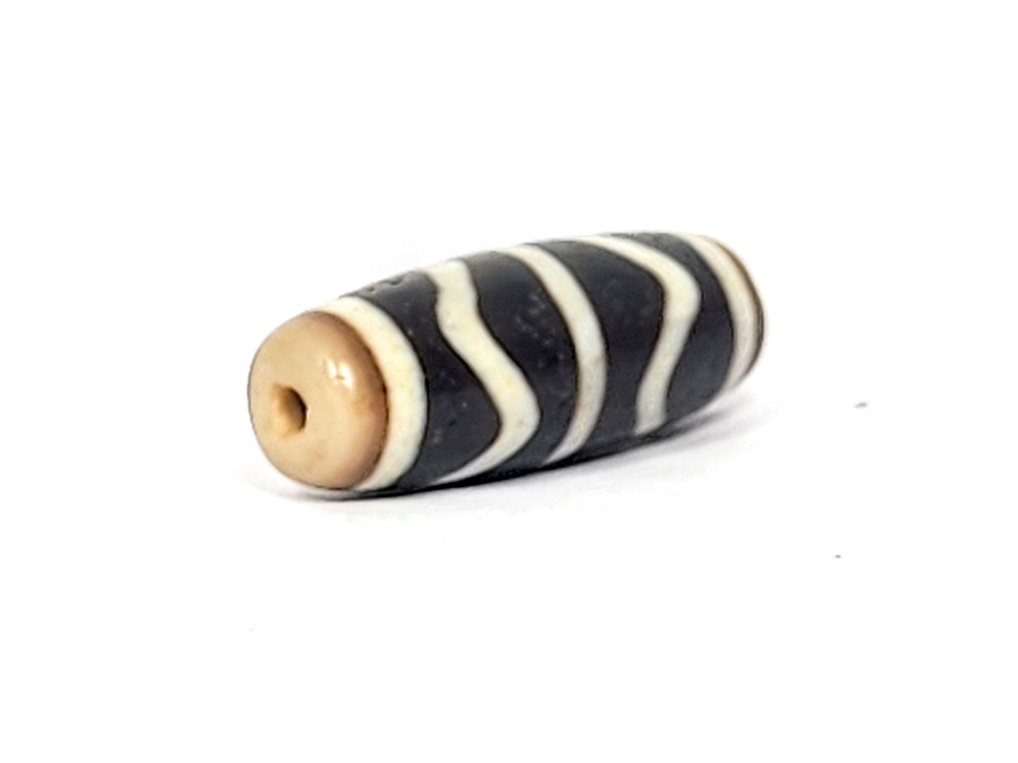 V-071425-DW vintage double wave dzi, other angled end shot, warm tan-brown drill end cap and drill hole visible, unretouched.