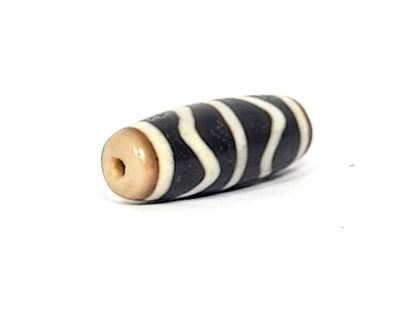 V-071425-DW vintage double wave dzi, other angled end shot, warm tan-brown drill end cap and drill hole visible, unretouched.