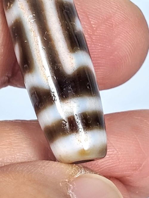 V-091424-GarudaBS Garuda dzi bead, macro showing scattered orange-rust cinnabar inclusions in cream field, unretouched