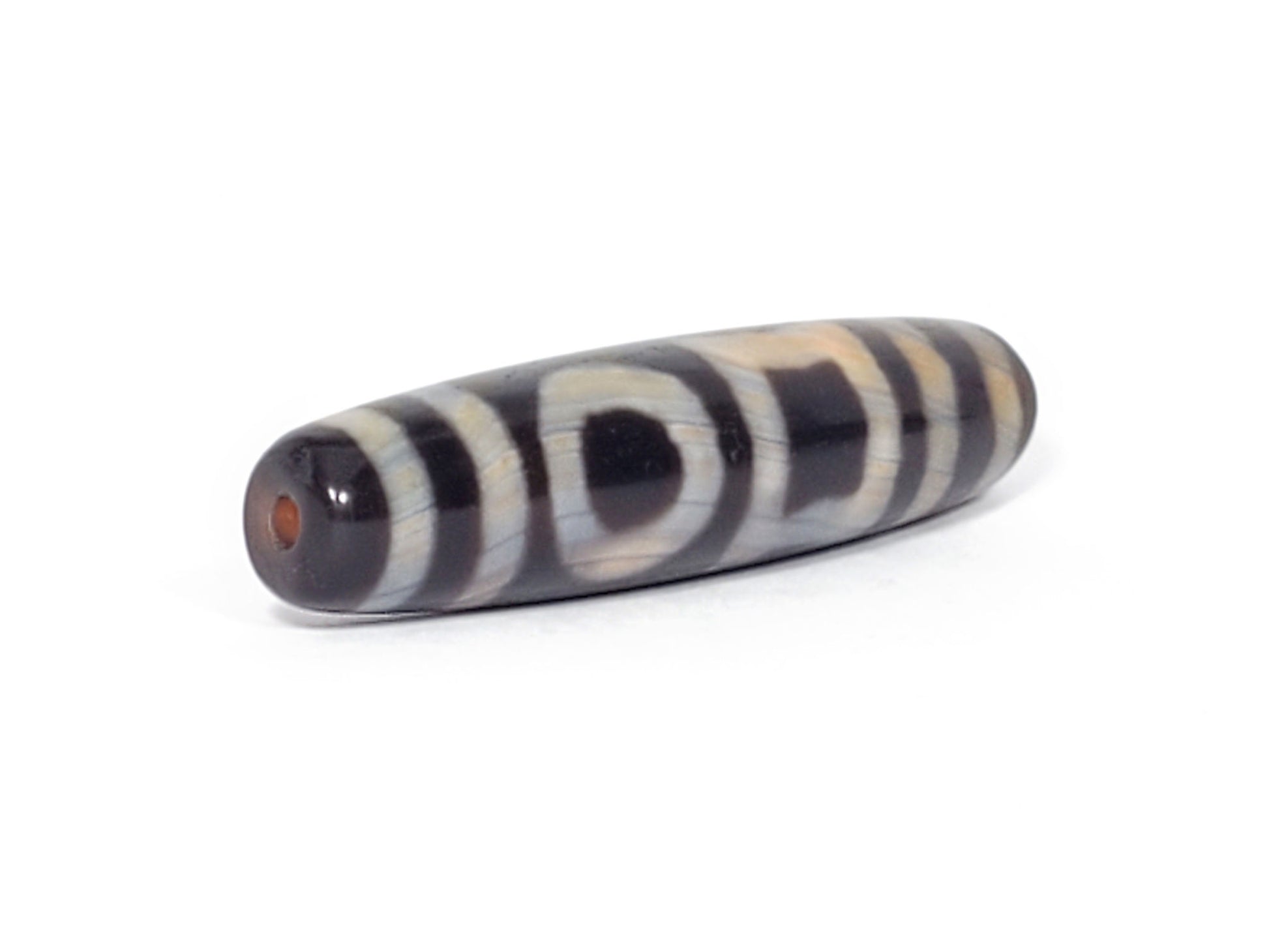 V-092723-DHE Double Heaven & Earth dzi bead, opposite angled end view, warm-toned drill tip, natural banding in motif lines, unretouched