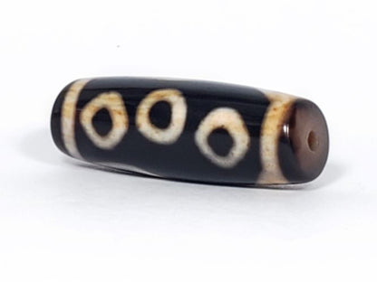 V-102723-6EBS Six Eye dzi bead, angled end view showing drill hole and warm brown end cap, unretouched