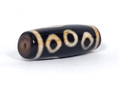 V-102723-6EBS Six Eye dzi bead, opposite angled end view, warm brown cap, pitch-black body, unretouched