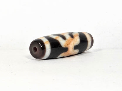 V-021326-BenBS Benefactor dzi bead, macro end cap zone, reddish-orange cinnabar in cream band, unretouched.