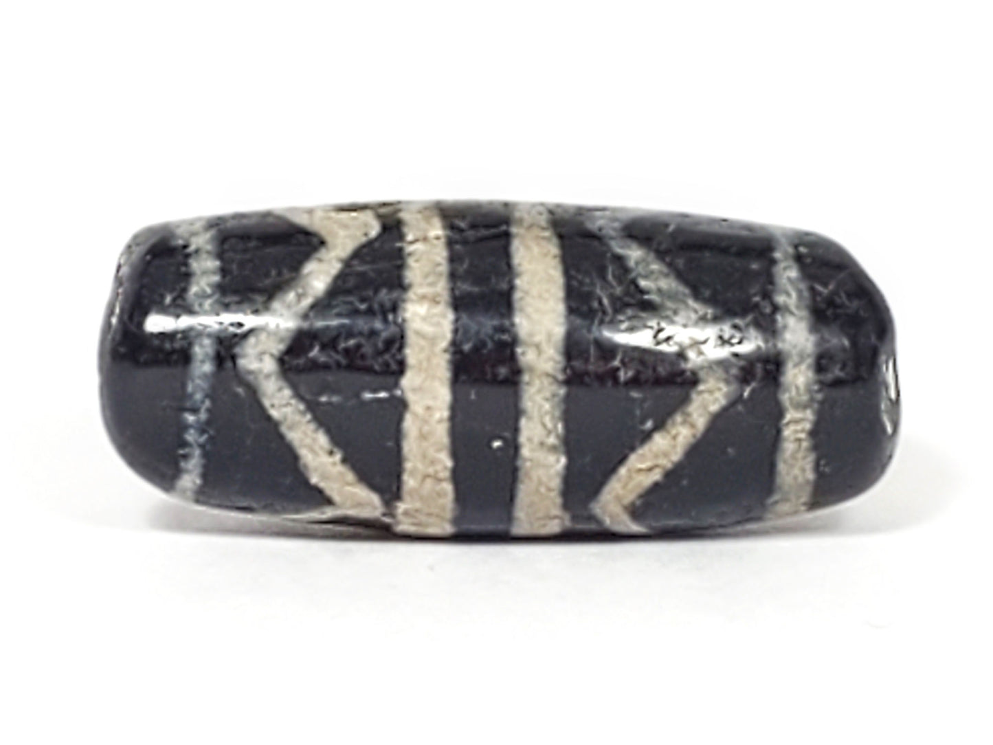Reverse side of ancient Double Tiger Tooth Dzi bead with visible surface weathering and calcification