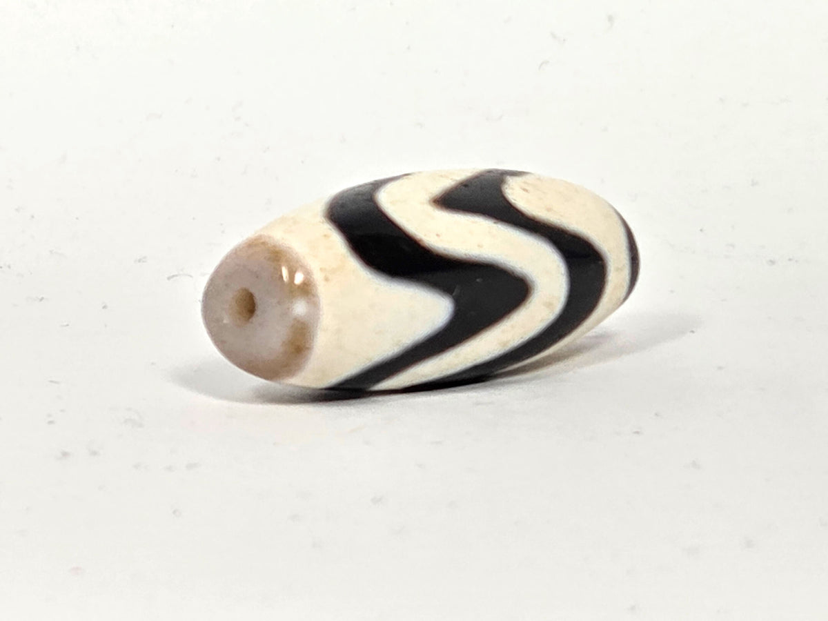 c-082524-DWBS, angled End A showing warm grey-taupe end cap and drilled hole, S-wave wrapping body, unretouched
