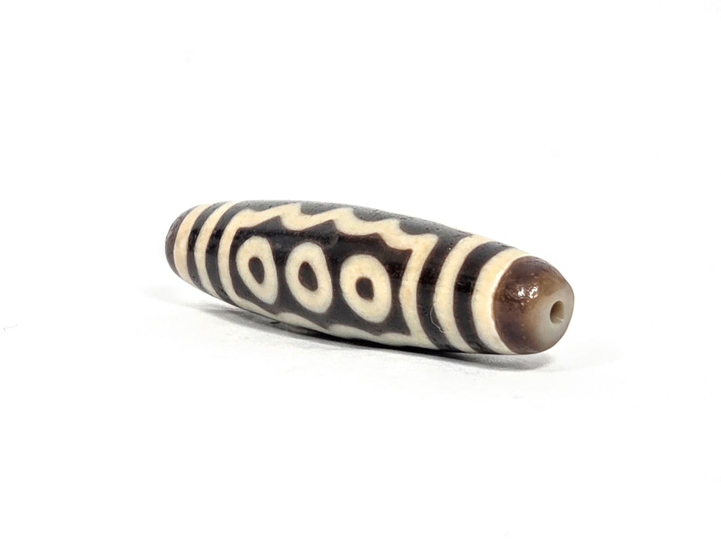 Ac-071026-7E ancient seven eye dzi angled view drill end A warm brown end cap small clean hole unretouched