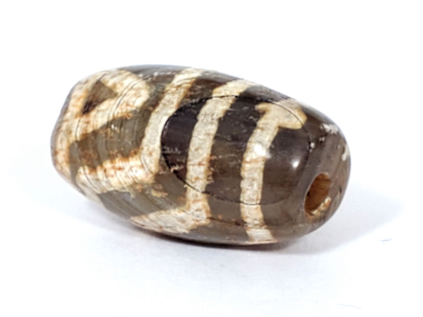 End view of ancient Two Eye Dzi — large drill hole, warm amber agate interior, cream pattern