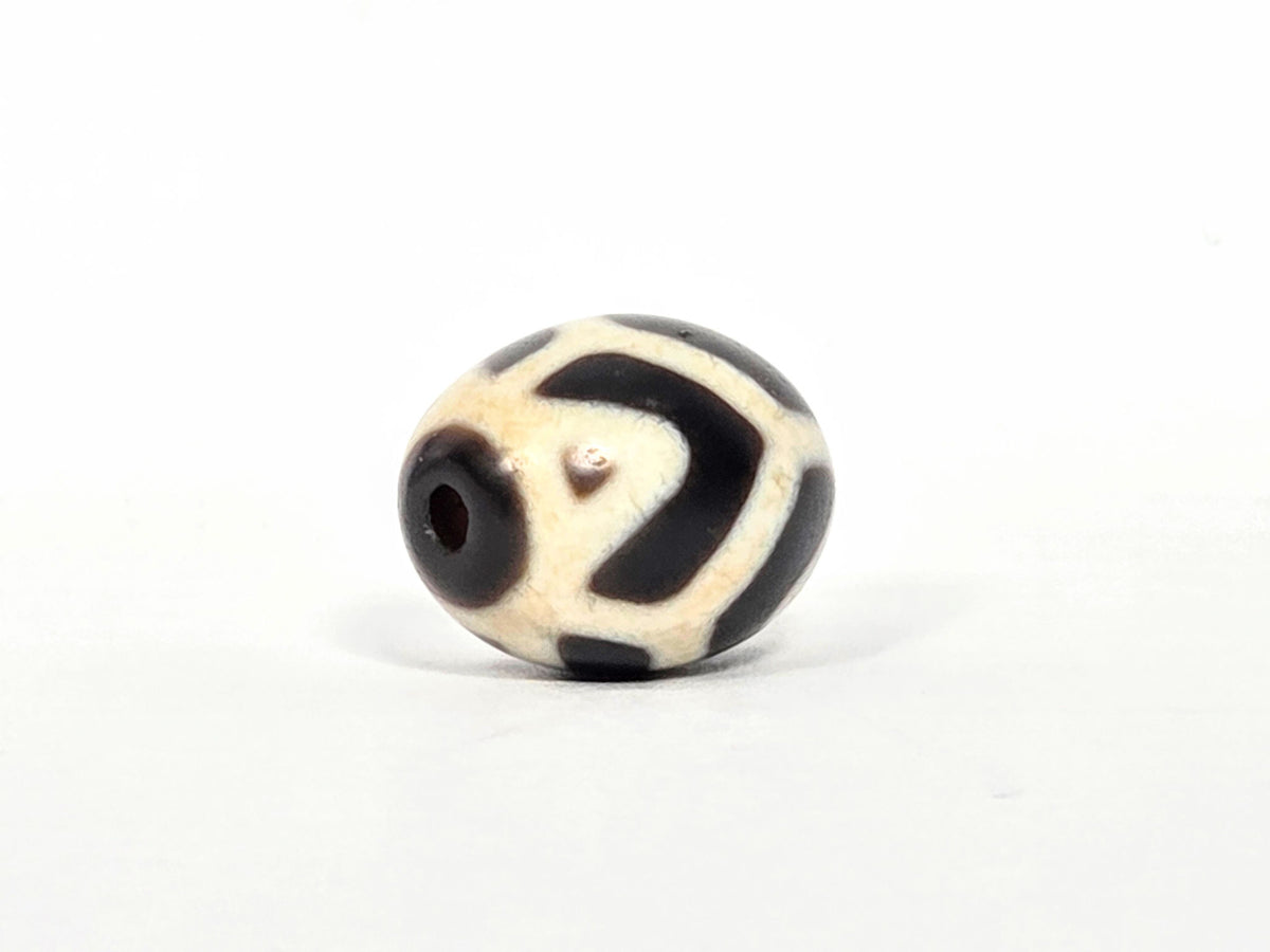 At-070826-RTTL antique round tiger tooth longevity dzi opposite drill-end view cream-ground dark motif wrap unretouched