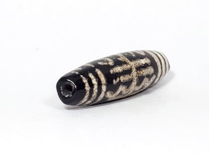 Second end of antique Waves & Bars Dzi — drill hole on deep black agate, wave and bar pattern visible