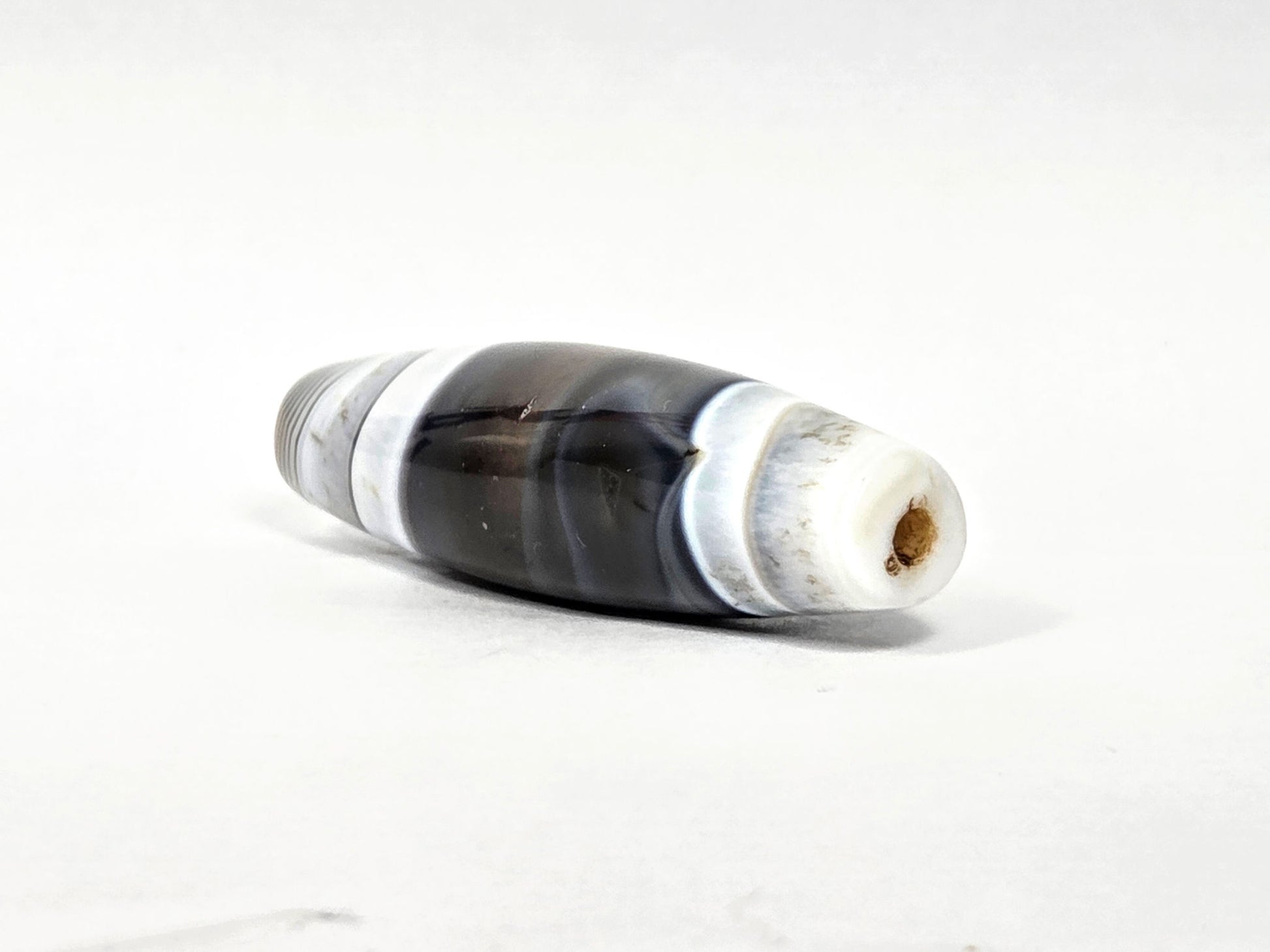 At-N-071426-NBA end angle A — wider end cap, concentric micro-banding, brown drill channel patina, unretouched.