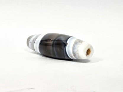 At-N-071426-NBA end angle A — wider end cap, concentric micro-banding, brown drill channel patina, unretouched.