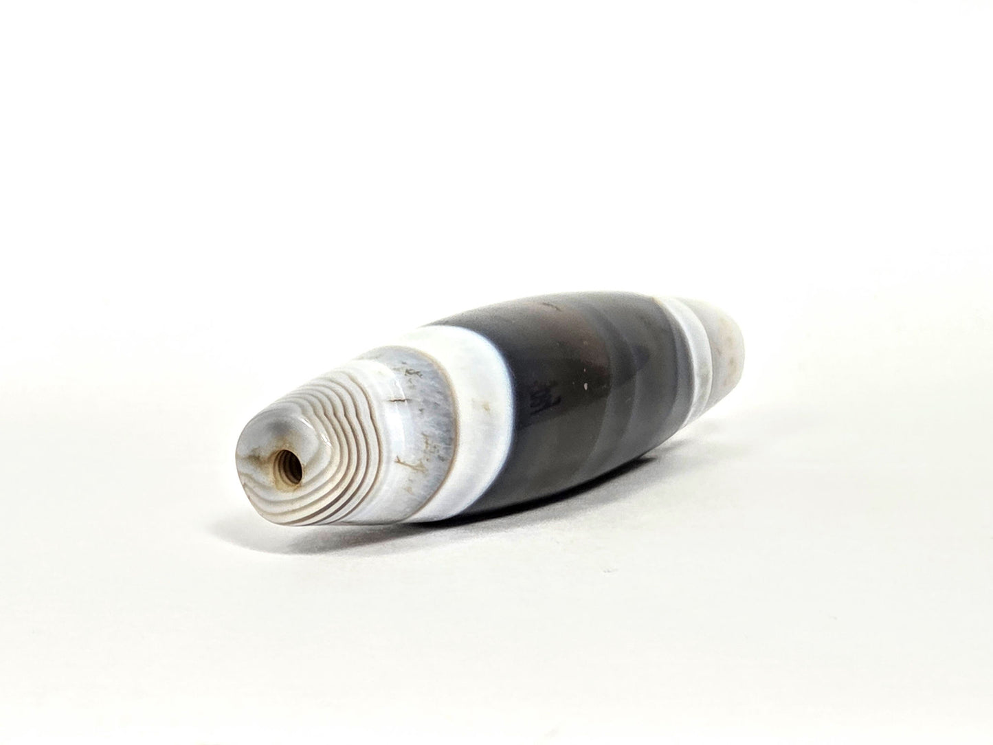 At-N-071426-NBA end angle B — narrower tapered end, dense concentric agate rings, drill opening visible, unretouched. 
