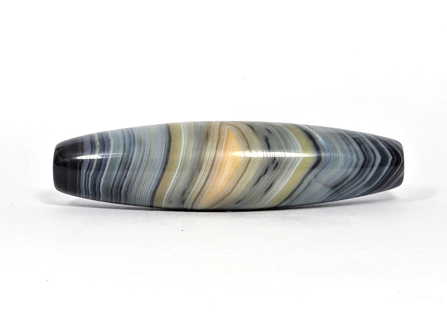 At-N-080426-1E2 antique natural one eye dzi bead 59.3×15.2mm, Face A showing resolved warm gold eye in blue-grey banded agate, unretouched