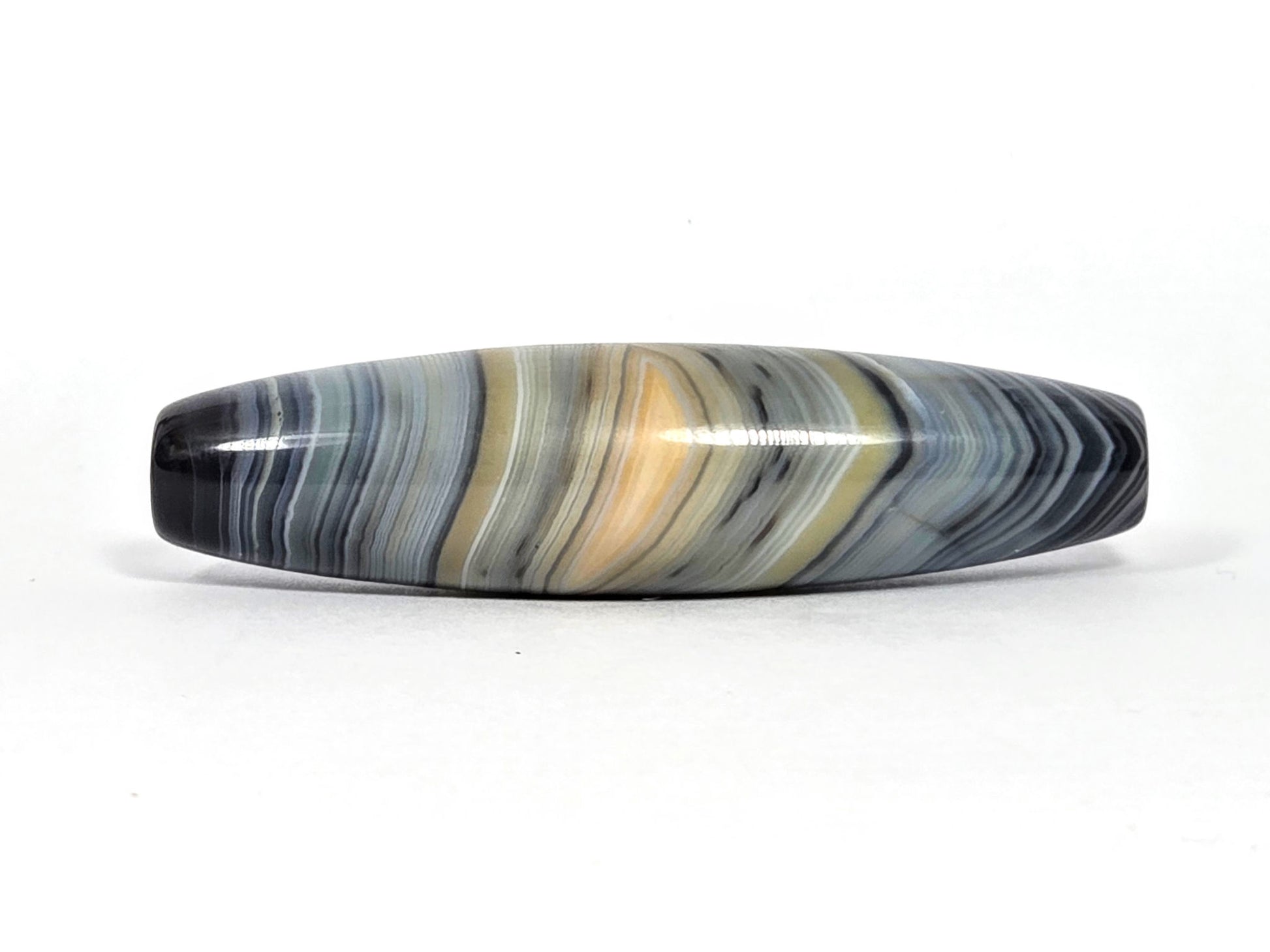 At-N-080426-1E2 antique natural one eye dzi bead 59.3×15.2mm, Face A showing resolved warm gold eye in blue-grey banded agate, unretouched