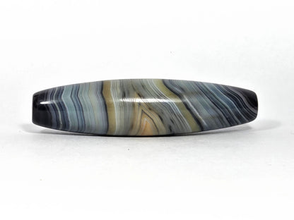 At-N-080426-1E2 antique natural one eye dzi bead 59.3×15.2mm, opposite turn showing fine parallel blue-grey and warm beige banding across full length, unretouched