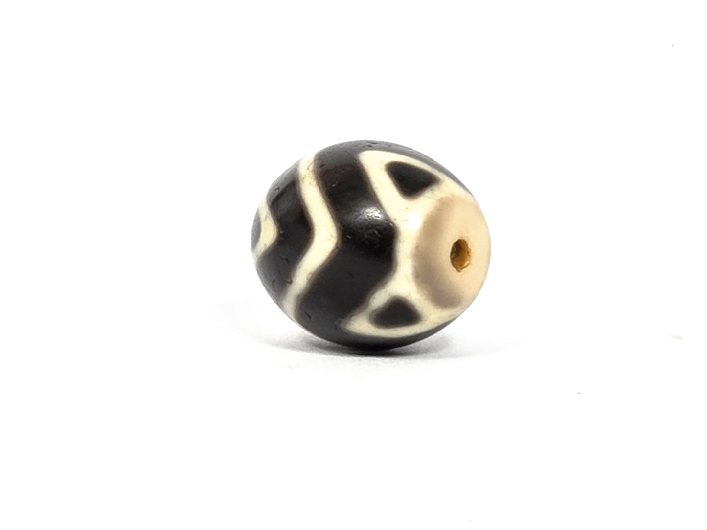 At-080926-WTT antique round Wave Tiger Tooth dzi bead 17.8×15.6mm, side rotation showing sinuous wave lines and cream drill-end cap on very dark brown ground, unretouched