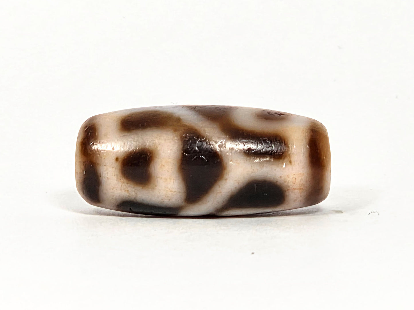 At-080926-6ELCBS antique Six Eye Lotus Cross dzi bead 24.1×10.8mm, Face C turn showing bracket element, connecting bar, and large oval on cream ground, unretouched