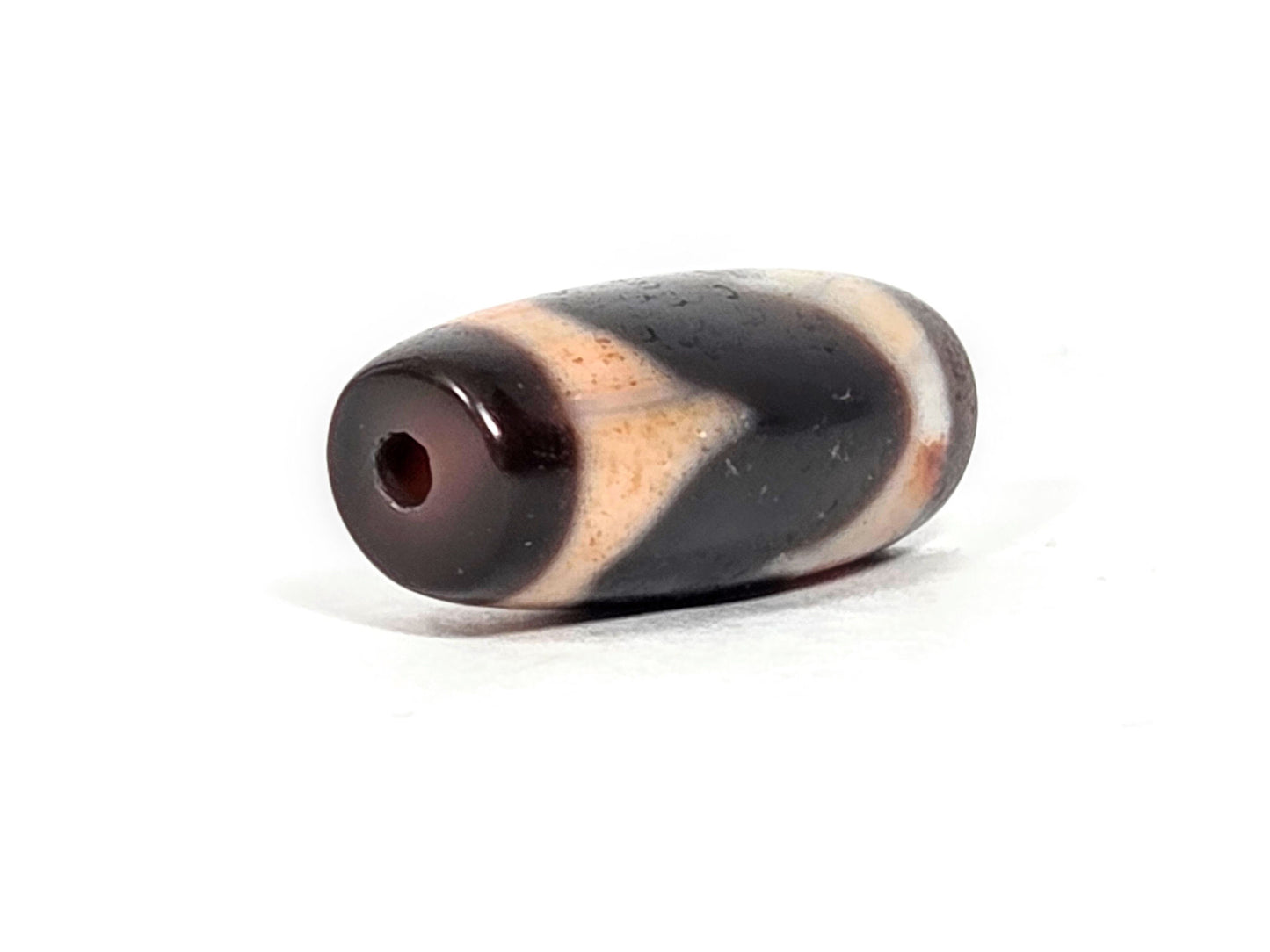 At-071426-TaBS4 end angle B — opposite warm reddish-brown end cap, pitch-black body, unretouched. 