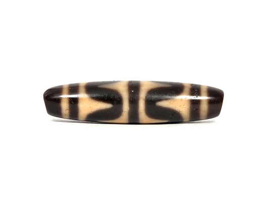 Antique Tibetan double wave dzi bead (AT-092926-DW4), first lateral profile showing dark brown and black opposing wave forms on honey-tan agate ground, 49.7 mm, 200–400 years old