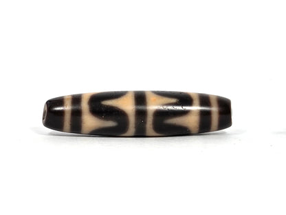 Second lateral profile of antique Tibetan double wave dzi bead showing reverse face with dark brown and black wave motif panels on warm honey-tan agate, 49.7 mm