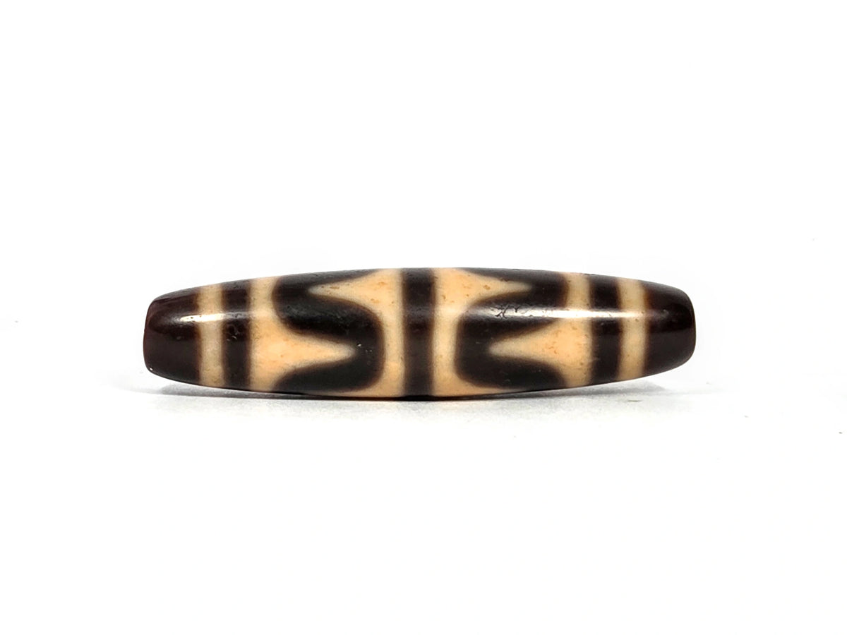Second lateral profile of antique Tibetan double wave dzi bead showing reverse face with dark brown wave motif panels and vertical stripe separators on warm honey-tan agate, 49.7 mm