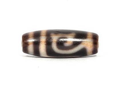 At-082326-GTBS antique Green Tara dzi bead 30.3×11.3mm, Face A showing cursive scroll motif on dark brown ground, cream lines with warm reddish-orange tinge, unretouched