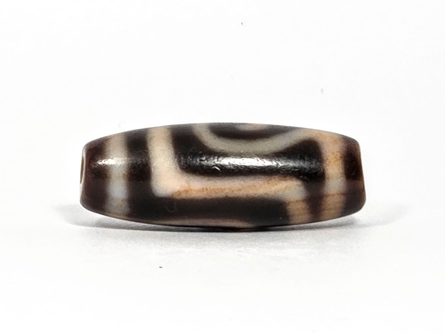 At-082326-GTBS antique Green Tara dzi bead 30.3×11.3mm, turn view showing Tara scroll continuing around shoulder with warm cream-honey zones, unretouched
